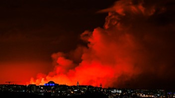 El horizonte de Reykjavik tiene como telón de fondo un cielo de color naranja debido a la lava fundida que fluye desde una fisura en la península de Reykjanes al norte de la ciudad evacuada de Grindavik, en el oeste de Islandia, el 16 de marzo de 2024. (HALLDOR KOLBEINS/AFP via Getty Images)