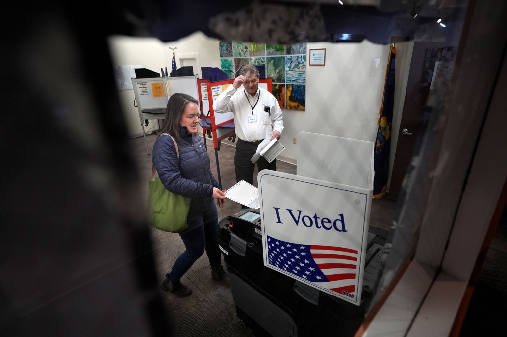 Amber Cutler emite su voto mientras el funcionario electoral Monte Mason observa durante la votación de las elecciones primarias el martes en el ayuntamiento de Morrisville en Vermont. (Robert F. Bukaty/AP)