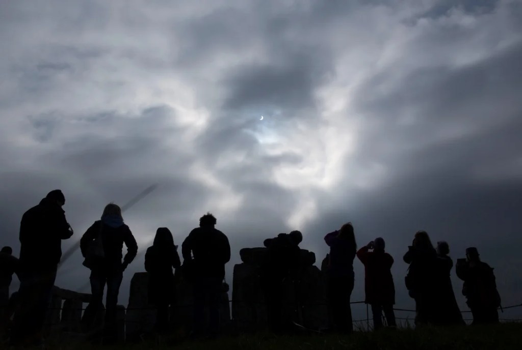 Un pequeño espacio en una capa de nubes cubiertas permite a los visitantes ver un eclipse solar desde Stonehenge, en el sur de Inglaterra, el 20 de marzo de 2015. (Foto :Kieran Doherty/Reuters).