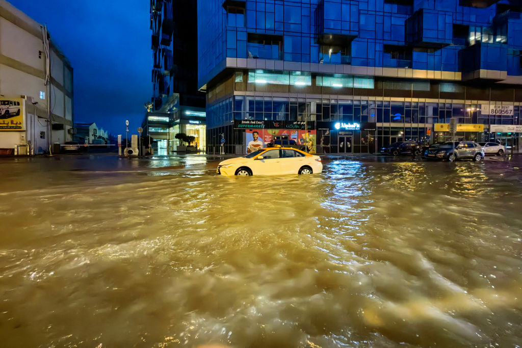 Un taxi circula por una calle inundada tras las fuertes lluvias en Dubai la madrugada del 17 de abril de 2024. (Crédito: GIUSEPPE CACACE/AFP vía Getty Images)