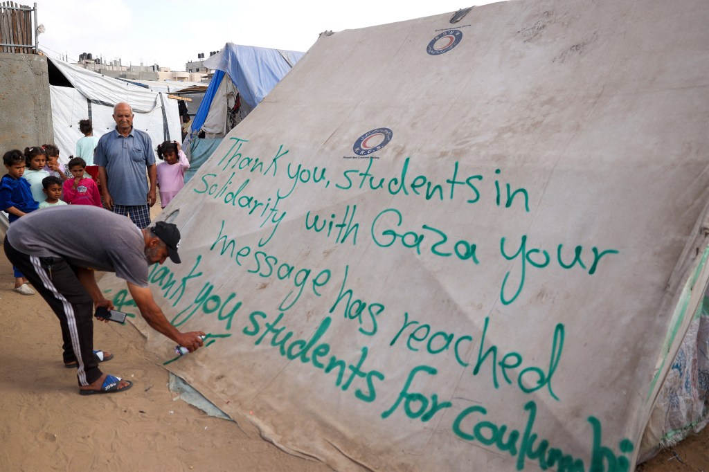 Un hombre escribe un mensaje de agradecimiento a los estudiantes estadounidenses que protestan en solidaridad con el pueblo de Gaza, en una tienda de campaña en un campamento para palestinos desplazados en Rafah, Gaza, el 27 de abril. (Foto: AFP/Getty Images).
