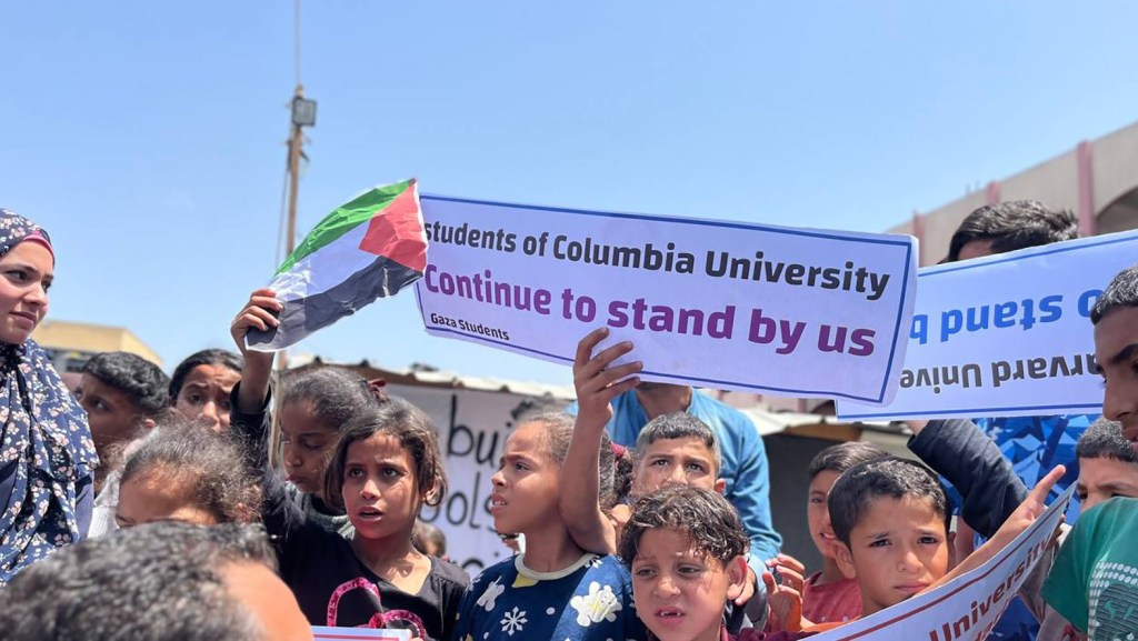 Palestinian students hold placards in Rafah, Gaza, on 28 April.  (Photo: Tarek Alhellou/CNN).