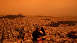 Una pareja sentada en la colina Tourkovounia en Atenas, mientras los vientos del sur transportan olas de polvo sahariano a Grecia, el 23 de abril de 2024. (Foto: Angelos Tzortzinis/AFP/Getty Images).