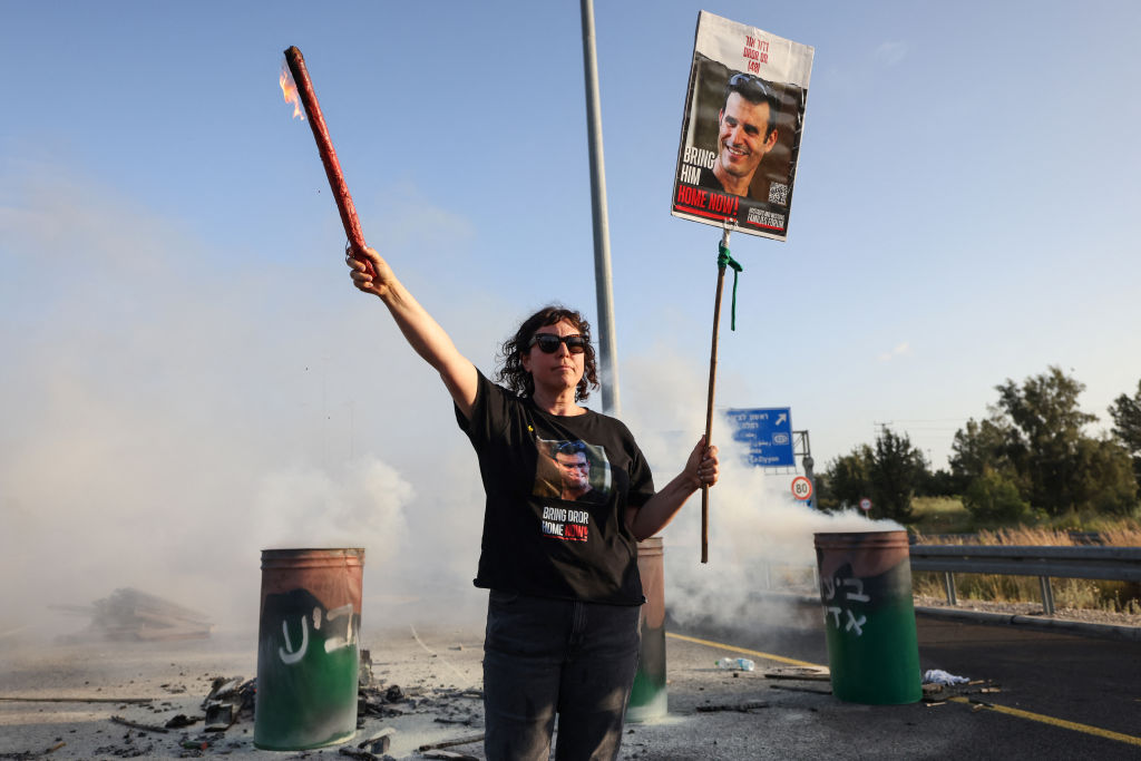 Una mujer sostiene un cartel con la imagen del rehén israelí Dror Or, de 43 años, mientras familiares y partidarios de los rehenes retenidos en Gaza desde los ataques del 7 de octubre. (Foto: AHMAD GHARABLI/AFP via Getty Images).