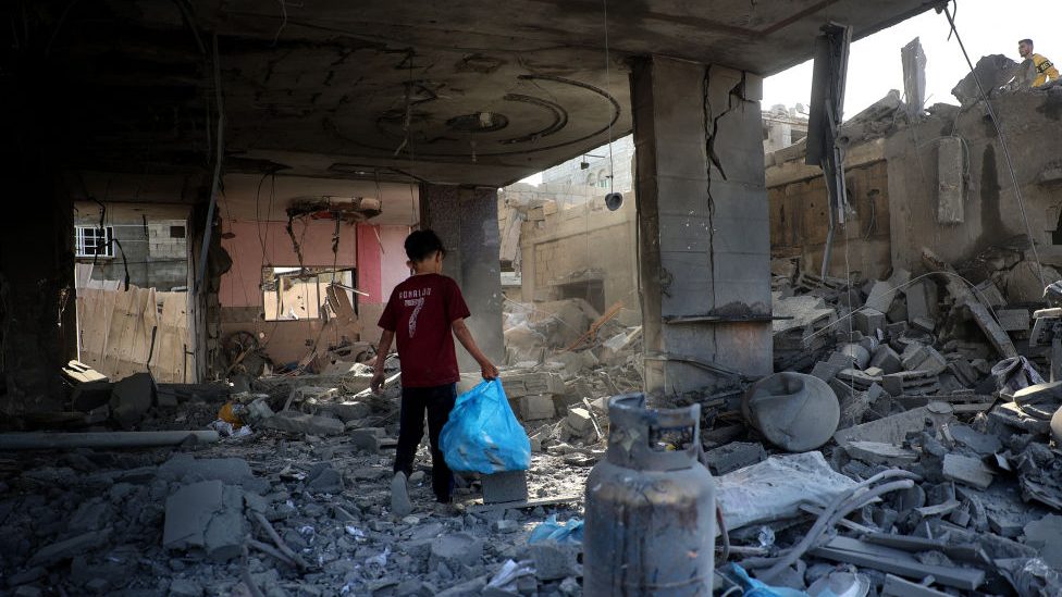 Un niño palestino lleva una bolsa entre los escombros de un edificio destruido por los bombardeos israelíes en Rafah, en el sur de Gaza, el 3 de mayo de 2024, mientras continúa el conflicto entre Israel y Hamas. (Foto: AFP vía Getty Images).