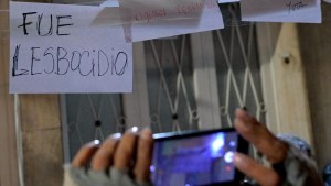 Una mujer toma una foto de una pancarta que dice "Fue lesbocidio" durante una vigilia frente a la casa donde dos mujeres lesbianas murieron en las primeras horas de la mañana del lunes en Buenos Aires el 8 de mayo de 2024. U(Foto de JUAN MABROMATA/AFP vía Getty Images)
