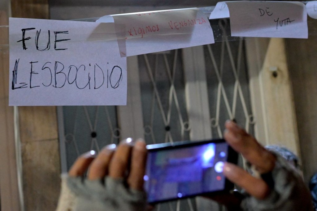 Una mujer toma una foto de una pancarta que dice "Fue lesbocidio" durante una vigilia frente a la casa donde dos mujeres lesbianas murieron en las primeras horas de la mañana del lunes en Buenos Aires el 8 de mayo de 2024. U(Foto de JUAN MABROMATA/AFP vía Getty Images)