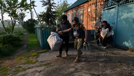 Voluntarios ucranianos ayudan a los residentes de los asentamientos en el norte de la región de Kharkiv durante su evacuación el 10 de mayo de 2024, en medio de la invasión rusa en Ucrania. (Foto de SERGEY BOBOK/AFP vía Getty Images)