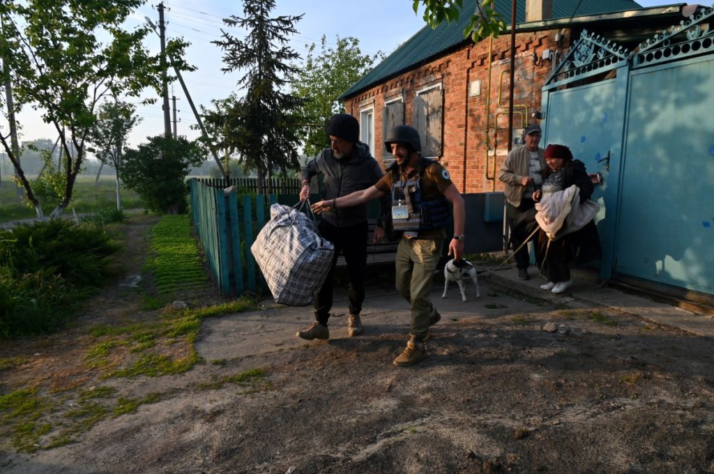 Voluntarios ucranianos ayudan a los residentes de los asentamientos en el norte de la región de Kharkiv durante su evacuación el 10 de mayo de 2024, en medio de la invasión rusa en Ucrania. (Foto de SERGEY BOBOK/AFP vía Getty Images)