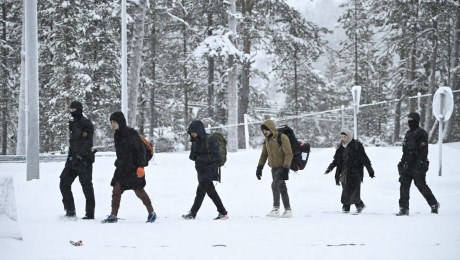 Agentes de la guardia fronteriza finlandesa escoltan a los migrantes a su llegada a la estación fronteriza de Raja-Jooseppi con Rusia en Inari, norte de Finlandia, el 25 de noviembre de 2023. (Foto de EMMI KORHONEN/Lehtikuva/AFP vía Getty Images)