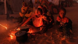 Refugiados recién llegados de Sudán cocinan comida en fogatas afuera de sus refugios improvisados, el 24 de abril de 2024 cerca de Adré, Chad. (Dan Kitwood/Getty Images)