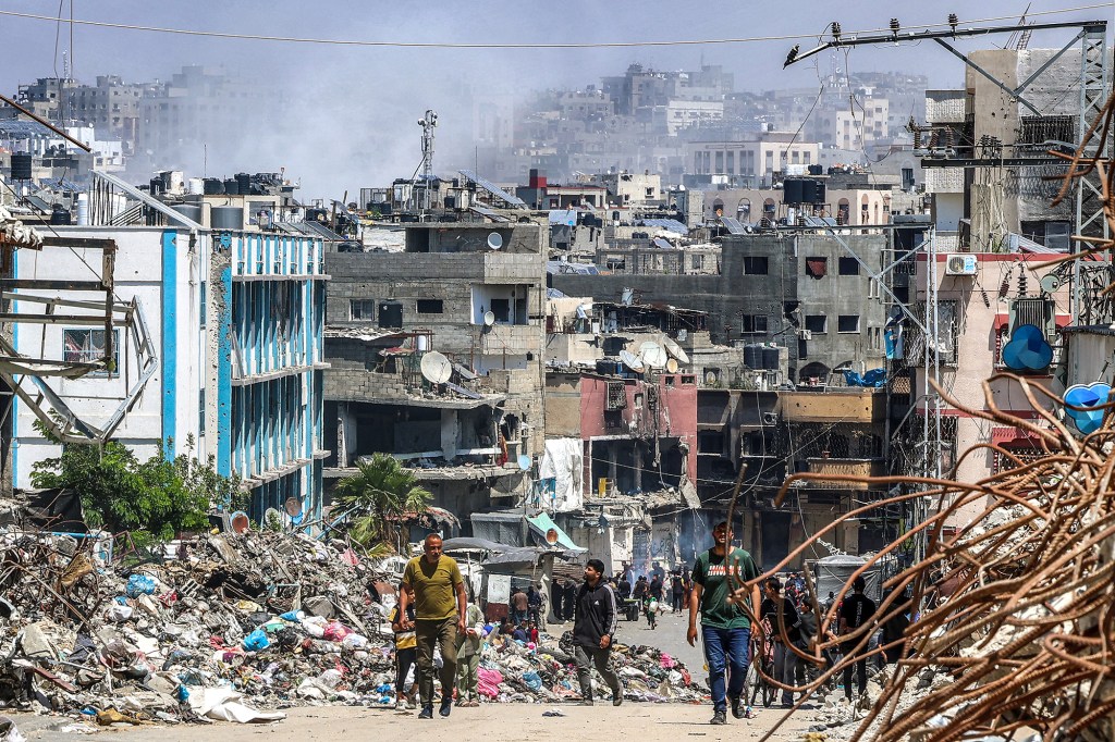 La gente pasa junto a un montón de basura y edificios destruidos en Jabalya, Gaza, el 14 de mayo. (Foto: AFP/Getty Images).