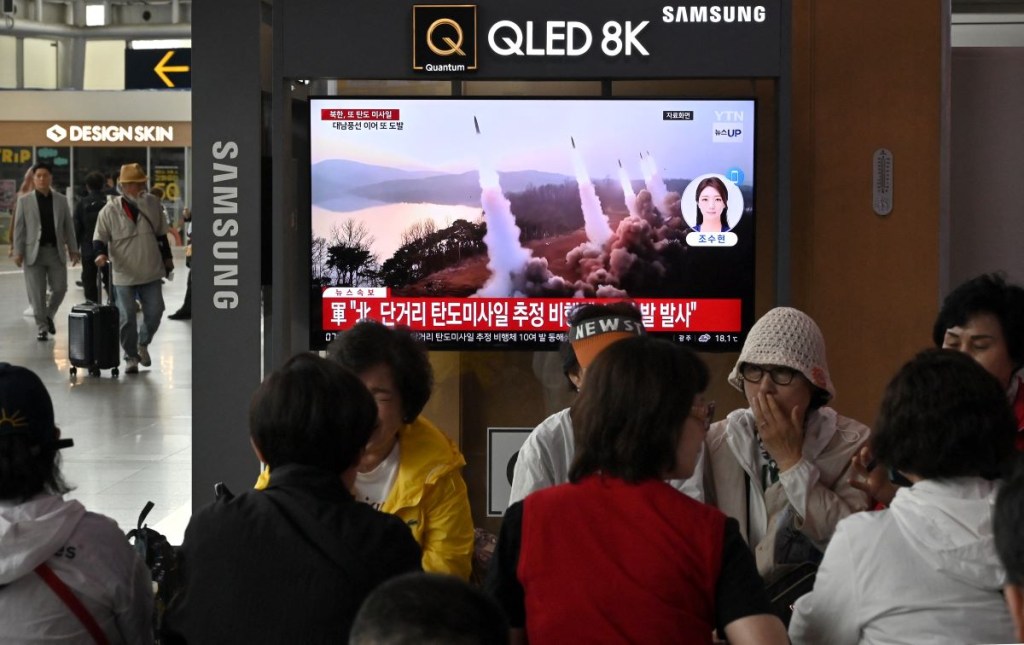 La gente ve una pantalla de televisión que muestra una transmisión de noticias con imágenes de archivo de una prueba de misiles norcoreanos, en una estación de tren en Seúl el 30 de mayo de 2024, hora local. (Foto de JUNG YEON-JE/AFP vía Getty Images)