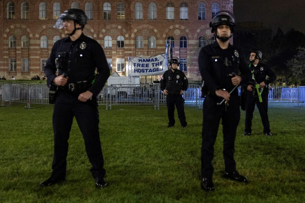 Agentes de policía estadounidenses hacen guardia frente a una pancarta que dice 