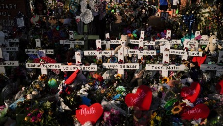 Se amontonan flores alrededor de cruces con los nombres de las víctimas que murieron en un tiroteo en una escuela mientras la gente visita un monumento en la Escuela Primaria Robb para presentar sus respetos el 31 de mayo de 2022, en Uvalde, Texas. (Jae C. Hong/AP)