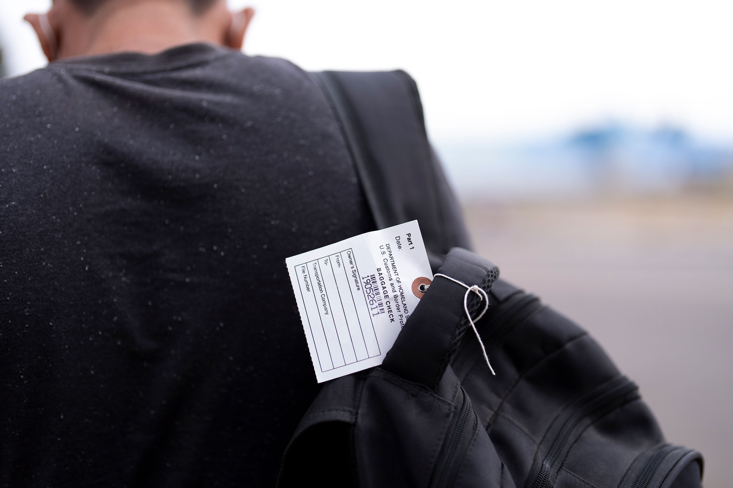 Un inmigrante en busca de asilo lleva una mochila con una etiqueta mientras busca opciones de transporte tras ser procesado y liberado, el martes 4 de junio, en San Diego. (Crédito: Gregory Bull/AP)