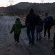 Solicitantes de asilo caminan para ser procesados ​​por agentes de la patrulla fronteriza en un campamento improvisado cerca de la frontera entre Estados Unidos y México en el este de Jacumba, California, el 2 de febrero de 2024. (Crédito: GUILLERMO ARIAS/AFP vía Getty Images)