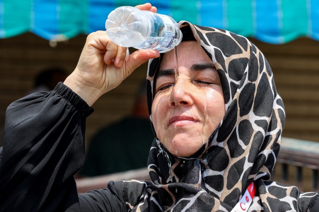 Una peregrina musulmana turca se vierte agua fría de una botella en la cabeza para refrescarse mientras espera en la ciudad santa de La Meca, en Arabia Saudita, el 20 de junio de 2024. (Foto de ABDEL GHANI BASHIR /AFP vía Getty Images)
