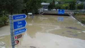 Una fotografía tomada el 30 de junio de 2024 muestra señales de tráfico sobre una carretera inundada cerca de Sierre, Suiza. (Crédito: BORIS HEGER/AFP vía Getty Images)