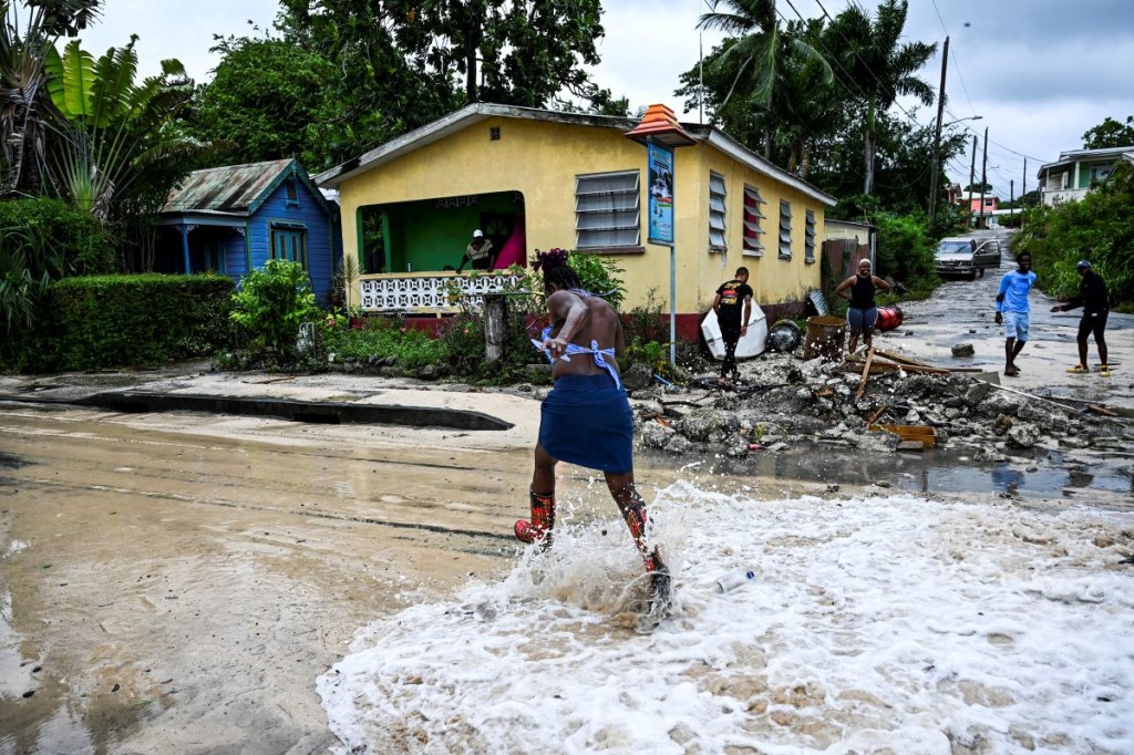 Una mujer pasa junto a un barco inundado después del paso del huracán Beryl en la parroquia de Saint James, Barbados, cerca de Bridgetown, Barbados. (CHANDAN KHANNA/AFP via Getty Images)
