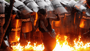 Un manifestante corre mientras cócteles Molotov caen al suelo frente a las fuerzas de seguridad durante las protestas contra los resultados electorales en Puerto La Cruz, Venezuela, el 29 de julio de 2024. (Samir Aponte/Reuters)