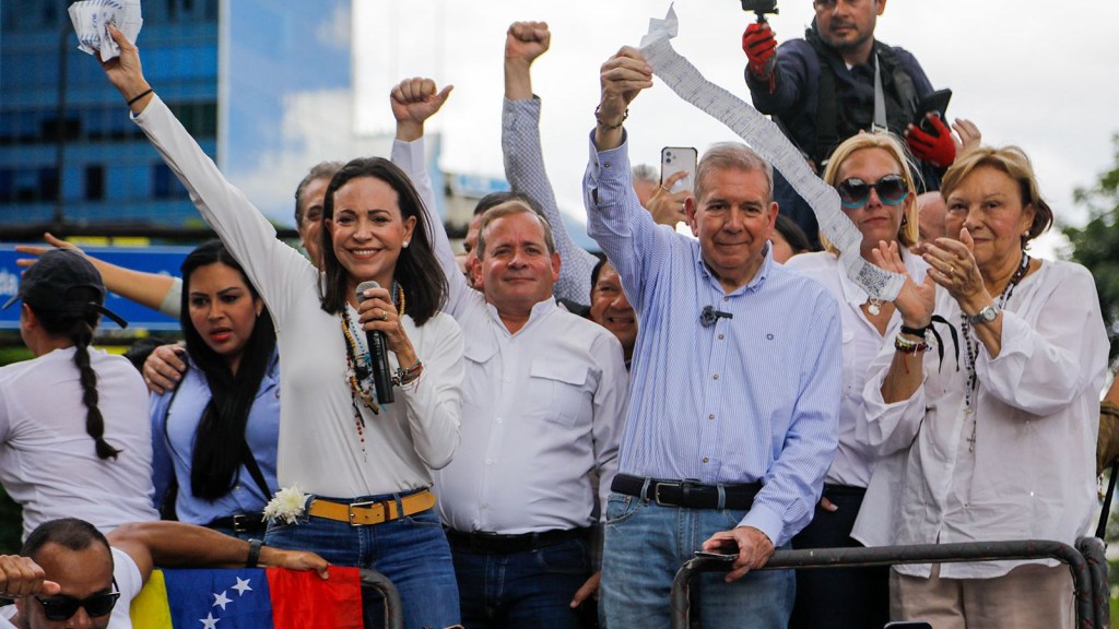 La líder opositora María Corina Machado y el candidato opositor Edmundo González sostienen hojas de recuento de votos desde lo alto de un camión durante una protesta en Caracas, Venezuela, el martes 30 de julio de 2024, dos días después de las elecciones. (Cristian Hernández/AP/Archivo)