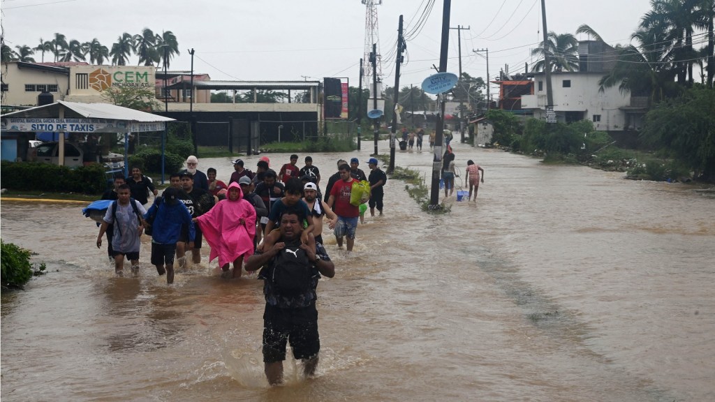 Varias personas caminan por una calle inundada en dirección a un refugio tras el paso del huracán John en Acapulco, estado de Guerrero. (FRANCISCO ROBLES/AFP vía Getty Images)