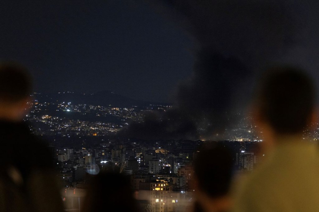 Periodistas y residentes locales observan desde una azotea mientras los ataques aéreos israelíes golpean los suburbios del sur de la ciudad el 1 de octubre de 2024 en Beirut, Líbano. (Foto de Daniel Carde/Getty Images)