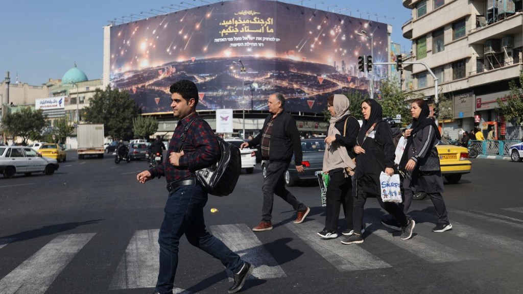 Iraníes caminan junto a una cartelera anti-Israel en una calle después de que se escucharon varias explosiones, en Teherán, Irán, el sábado. (Majid Asgaripour/Wana News Agency/Reuters)