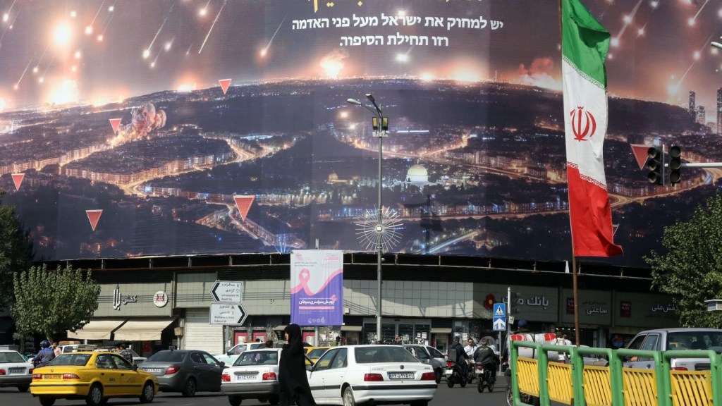 La gente camina por las calles de Teherán donde se ven banderas iraníes y pancartas de Hezbollah, mientras continúan las tensiones entre los dos países después del ataque con misiles de Irán contra Israel en Teherán, Irán, el 9 de octubre de 2024. (Fatemah Bahrami/Anadolu/Getty Images)